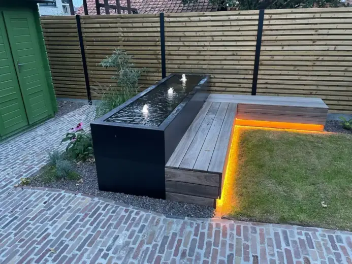 Perfect onderhouden gazon en borders in een landelijke tuin ontworpen door Tuinen Geoffrey Debergh in Elverdinge